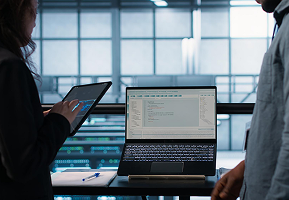 An engineer working on a laptop beside an office window