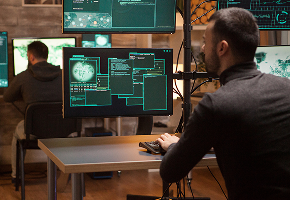 A security analyst reviewing code on a multi-monitor workstation